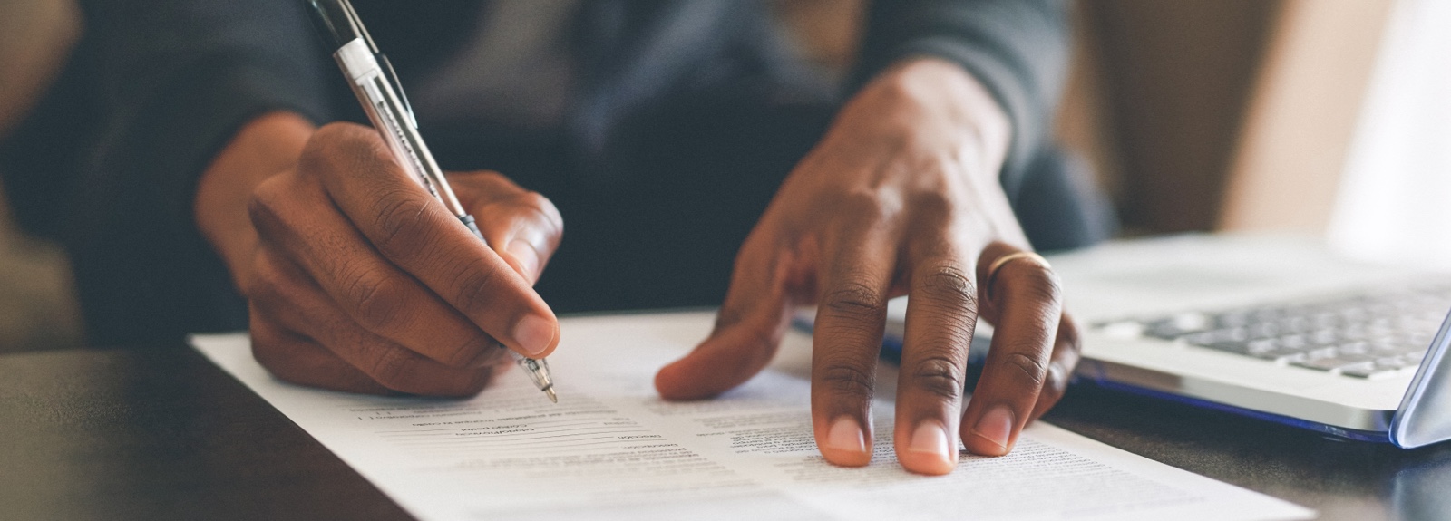 Close up of a person's hands signing a document
